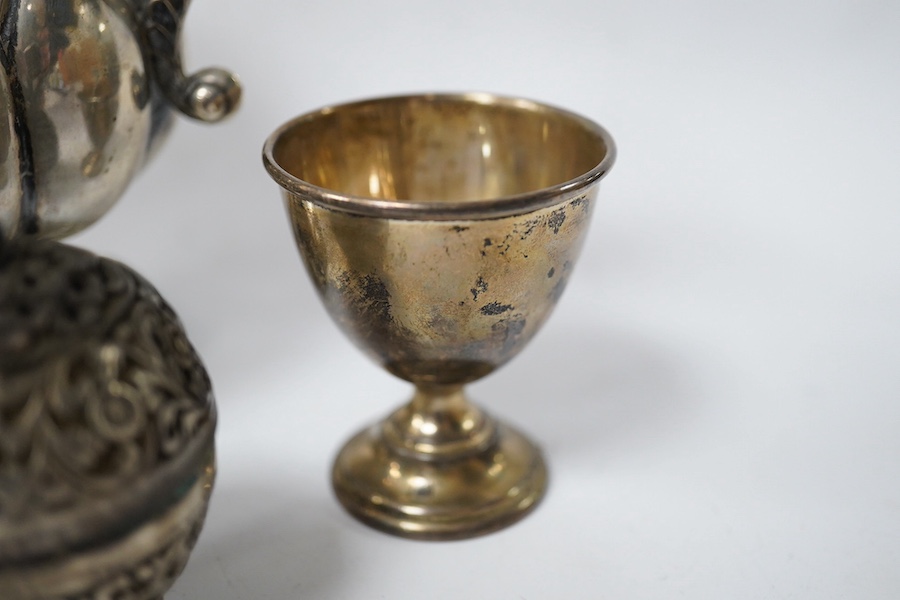 An Indian white metal three piece condiment set, a continental white metal jug, height 14cm, a silver egg cup and an engraved white metal hinged bangle. Condition - poor to fair